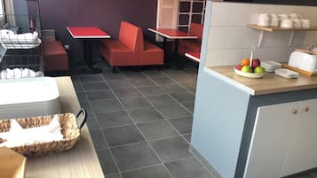 A restaurant with red seating, a counter with a fruit bowl, and a toaster.