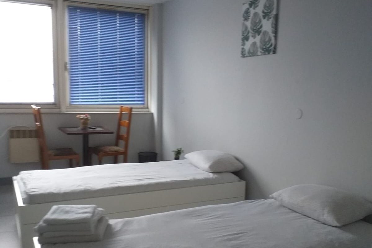 A room with two beds, a small table, and a chair.