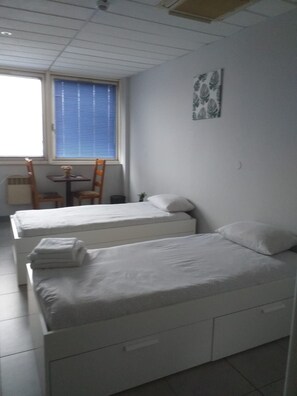 A room with two beds, a small table, and a chair. - Appart Hotel (Champagne-sur-Oise)