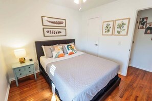 A bedroom with a bed, a nightstand, and a door.