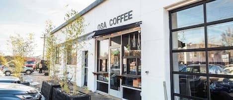 Un café appelé OSA COFFEE, doté de grandes fenêtres et d’un parking situé devant l’établissement.