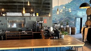 A bar area with a wooden counter, a beer tap station, and a mural with a wave pattern. - The Eastside 2BR Near 5Points (Nashville)