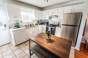 A modern kitchen with white cabinets, stainless steel appliances, and a wooden island.