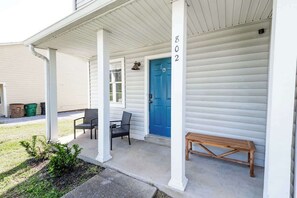 A covered porch with a blue door, numbered 802, and two chairs. - Riverside Retreat Near 5 Points (Nashville)