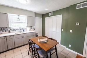 A compact kitchen with a dining table, chairs, and a window with blinds. - Riverside Retreat Near 5 Points (Nashville)