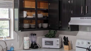 Une cuisine avec des meubles de couleur sombre, un four à micro-ondes, un mixeur et un évier.