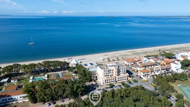 Ein Luftbild einer Küstenstadt mit Strand, einer Yacht sowie einer Mischung aus Wohn- und Geschäftsgebäuden.