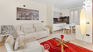 Ein modernes Wohnzimmer mit einer Couch, einem Essbereich mit Tisch und Stühlen, einer Küche im Hintergrund und einem Stadtbild an der Wand.