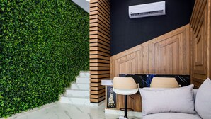 Eine moderne Hotelhalle mit einer grünen Wand, einer Treppe, einer Wand aus Holzpaneelen und einer Sitzecke mit Sofa und Lampe.