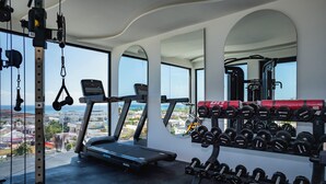 Ein Fitnessraum mit Laufband, Hantelbank und Kurzhanteln.