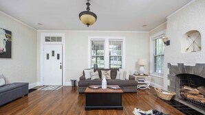 A living room with hardwood floors, a gray sofa, a coffee table, a fireplace, and a ceiling light fixture.