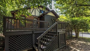 A wooden deck with a staircase leading to a building with a brick facade and a window.