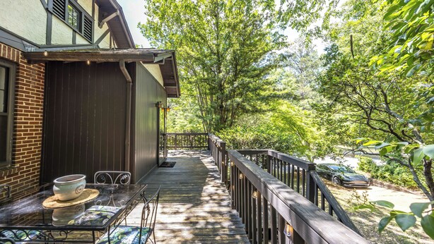 A wooden deck with a table and chairs, surrounded by trees.