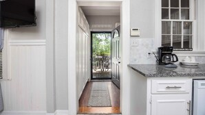 A kitchen with a built-in TV, a coffee maker, and a window with a view of the outdoors.