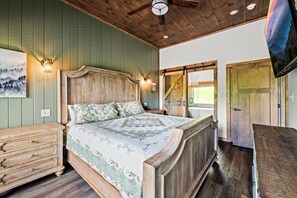 Een slaapkamer met een houten bed, een kapstok, een wandlamp en een deur met uitzicht.
