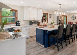 Une cuisine moderne avec des meubles blancs, un îlot central et un coin repas doté de chaises noires.