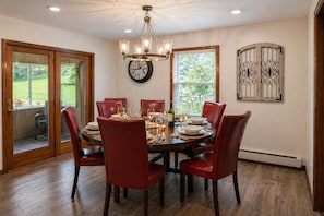 Une salle à manger avec une table ronde, des chaises rouges, un lustre et une horloge au mur.