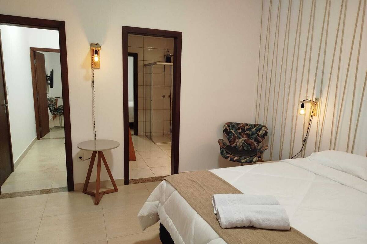 Une chambre d’hôtel avec un lit, une table ronde, une chaise et un miroir.