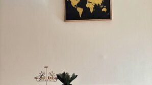 A dining area with a table covered by a black tablecloth, a wooden chair, a small potted plant, and a decorative metal piece. - Spacious apartment with pool, 5-minute walk from the beach (Le Gosier)