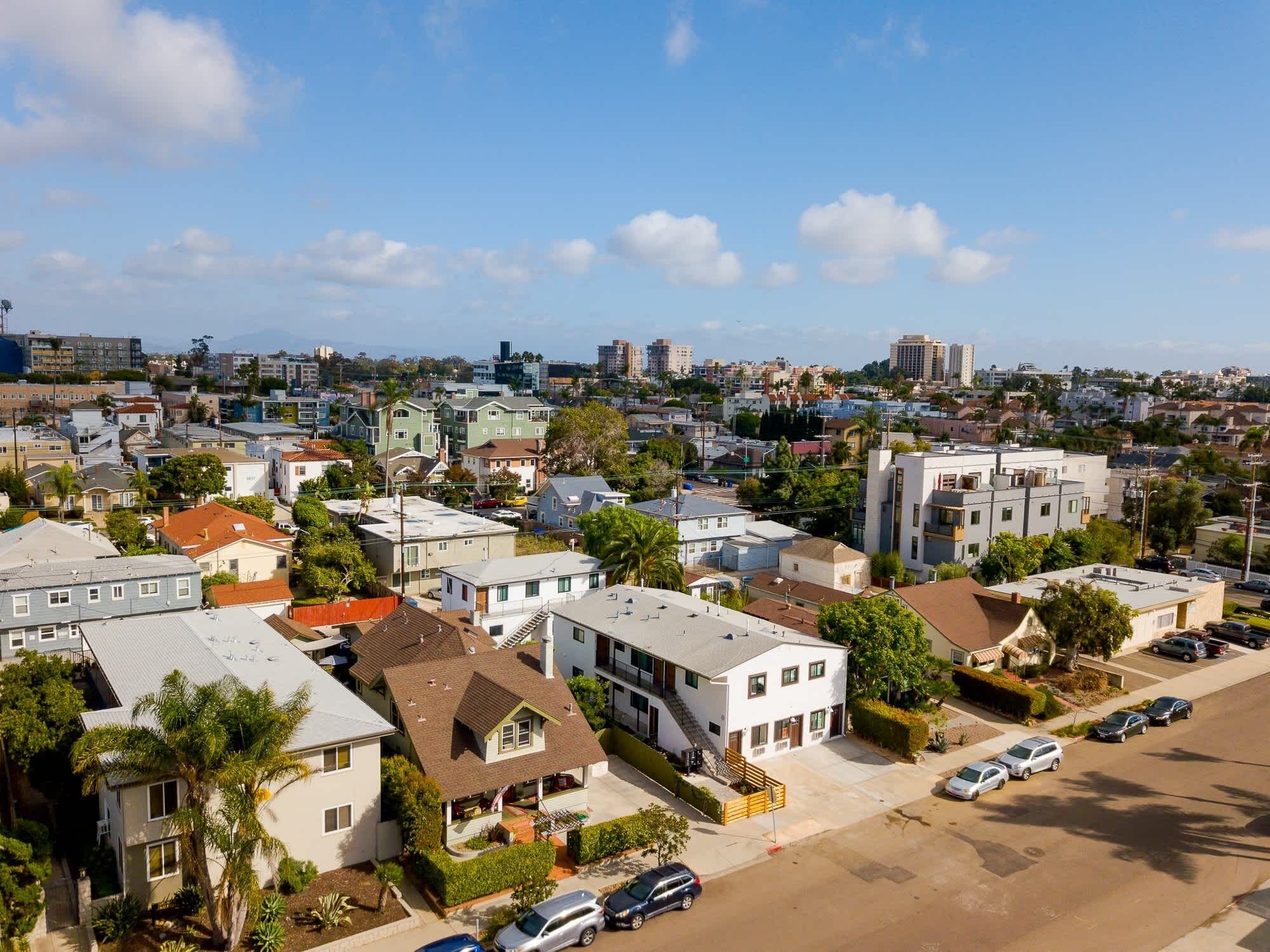 A residential area with houses, a parking lot, and a clear sky.