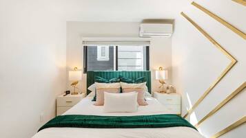 A neatly arranged bedroom with a bed, bedside tables, lamps, and a window.