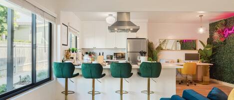 A modern kitchen with a central island, bar stools, and a blue sofa.