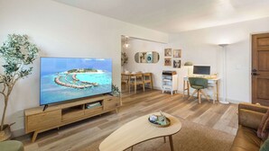 Un salon moderne doté d’un téléviseur à écran plat, d’un meuble de rangement en bois, d’un coin repas, d’un espace de travail et d’un coin salon confortable.
