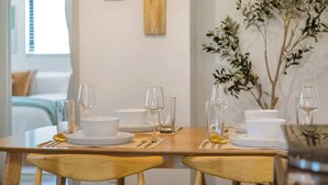 Une table à manger dressée avec de l’assiette blanche, des verres et des couverts, et une chaise en bois au premier plan.