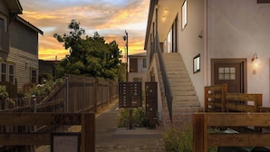 Une rue résidentielle avec un portail en bois portant le numéro « 3833 », une boîte aux lettres et un escalier menant à un immeuble doté d’un luminaire.