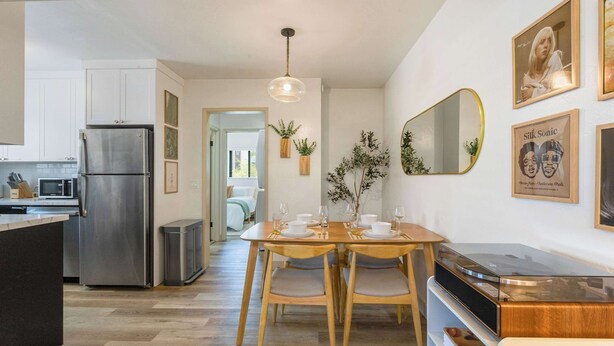 Une cuisine moderne avec un coin repas, un réfrigérateur en acier inoxydable, une table à manger en bois et une platine vinyle.