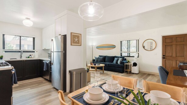 A modern kitchen with dark cabinets, a stainless steel refrigerator, and a dining area with a table set for four.