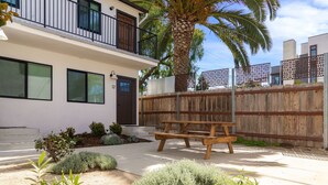 A two-story house with a balcony, a wooden fence, and a palm tree.