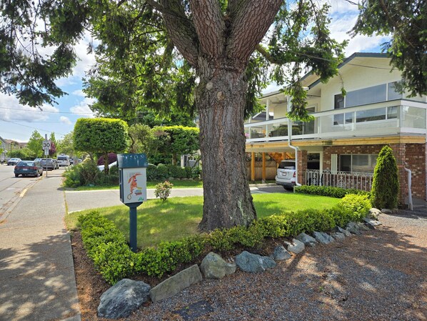 A residential area with a two-story house, a driveway, and a street sign indicating a 30 km/h speed limit. - Furnished 1900sf 3bedr house in downtown Sidney one block from Ocean and shops (Sidney)