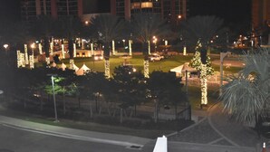 A nighttime view of a well-lit urban area with trees adorned with lights, a grassy area, and a building in the background. - APARTAMENTO ENTERO REFORMADO A NUEVO (Sunny Isles Beach)