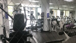 A gym with various exercise machines, mirrors, and a ceiling with square lights. - APARTAMENTO ENTERO REFORMADO A NUEVO (Sunny Isles Beach)