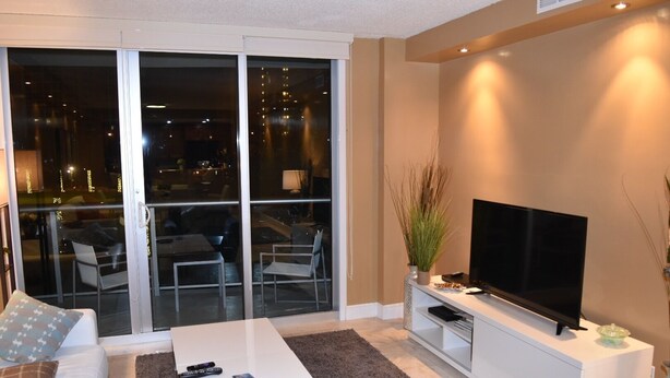 A living room with a flat-screen TV, a white coffee table, and a sofa. - APARTAMENTO ENTERO REFORMADO A NUEVO (Sunny Isles Beach)