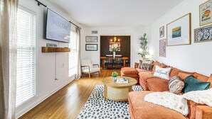 Un salon avec un téléviseur, un canapé, une table basse et, au fond, un coin repas.