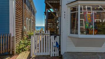 Un étroit sentier mène à un bâtiment blanc doté d’une baie vitrée et d’une clôture en bois.