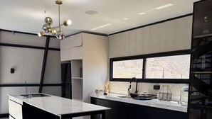 A modern kitchen with a central island, black cabinetry, and a view of a mountainous landscape through a large window. - Only 30 min from Trujillo: Luxury retreat in the mountains ideal for disconnecting (Simbal)