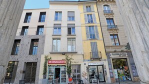 A street view with a pharmacy, a market, and a building with a balcony. - Ticinese 28 Apartment (MILANO)