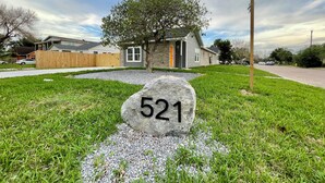 Een woonhuis met een steenplaquette met het nummer '521' in de voortuin, omgeven door gras en grind.