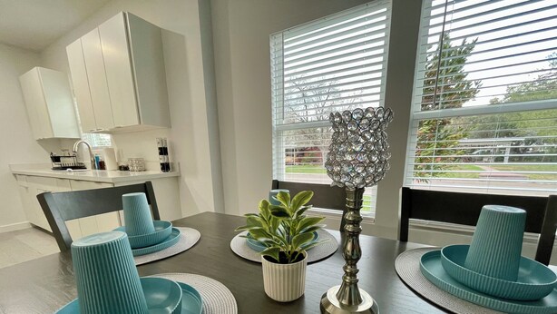Een moderne eetruimte met een donker houten tafel, tealkleurige borden en een decoratieve kristallen lamp.