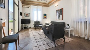 A living room with a sofa, armchair, coffee table, and TV.