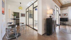 A modern kitchen with bar stools, a dining area with a table and chairs, and a television.