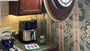 A kitchen with a coffee maker, kettle, and a decorative plate on the counter.