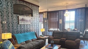 A living room with a sectional sofa, a coffee table, a patterned rug, and a skylight.