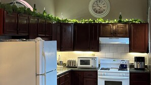 A kitchen with dark wooden cabinets, a white refrigerator, a stove, a microwave, and a chandelier.