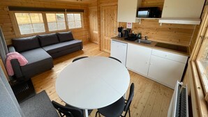 Una cabaña compacta con kitchenette, comedor y sofá.
