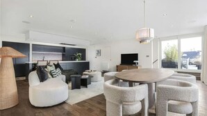 A modern living room with a sofa, a round dining table, and a kitchen area in the background.