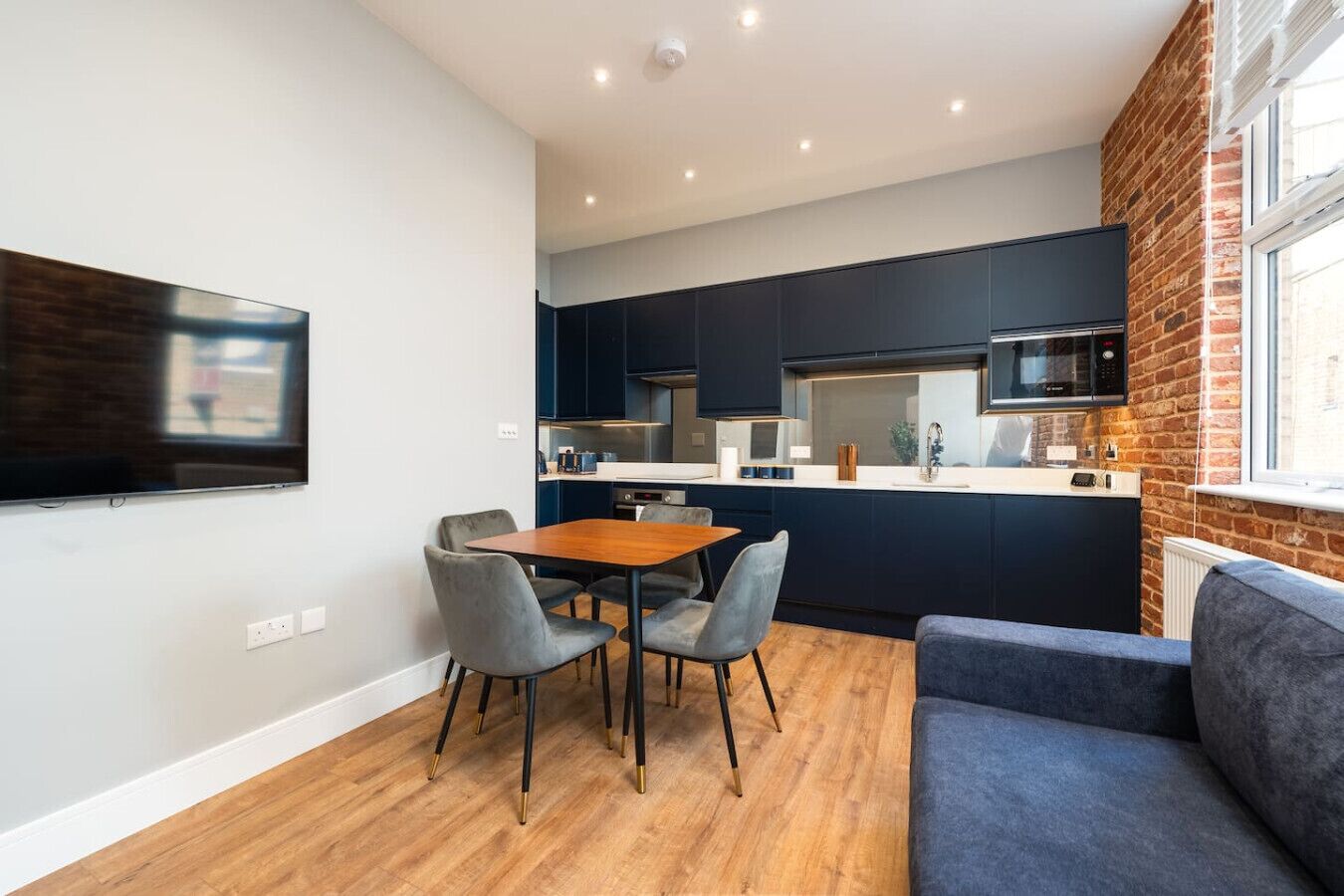 A compact living space with a dining area, kitchenette, and a seating area with a sofa.